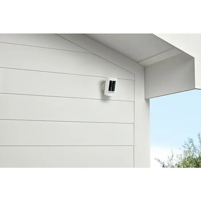 Ring Überwachungskamera außen Stick Up Cam Battery - Akkubetrieben, 1.080 Pixel (Full HD), Weiß - Nahaufnahme einer Ring Stick Up Cam, die an einer weißen Hauswand montiert ist und Sicherheit bietet.
