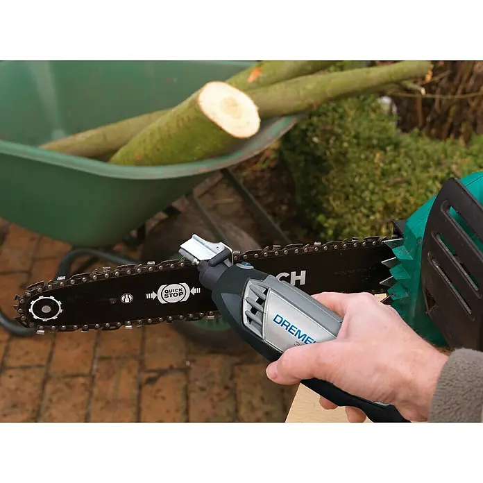 Dremel Set para afilar cadenas de motosierras - Específico para: Herramientas multifunción Dremel (excepto la 4200), 9 pzs. - Primer plano de un afilador de motosierra Dremel afilando una motosierra, con una carretilla de madera al fondo.