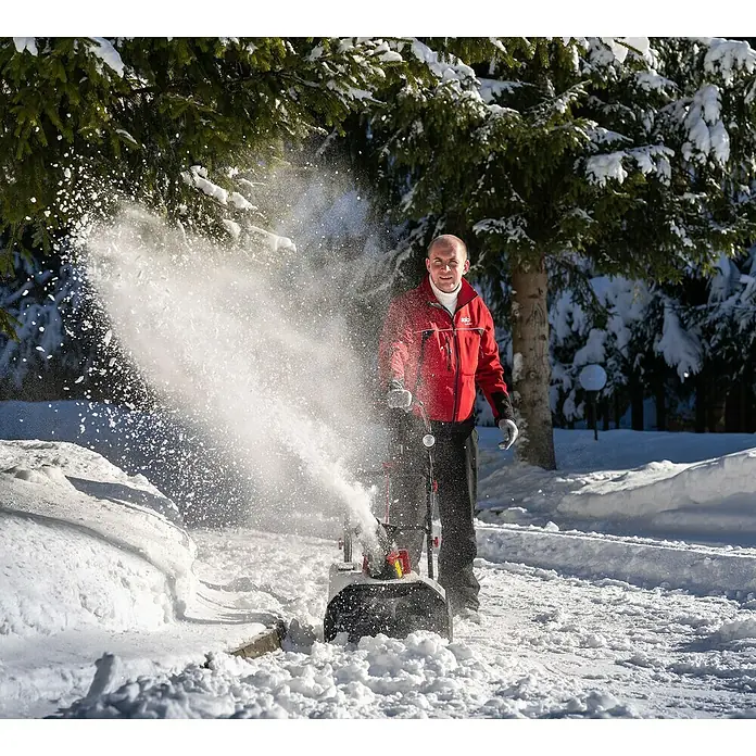 AL-KO 36V Akku-Schneefräse ST4048 - 40 V, 1 Akku, Arbeitsbreite: 48 cm - Ein Mann benutzt eine Schneefräse, um einen Weg von Schnee zu befreien. Die Schneefräse schleudert den Schnee zur Seite.