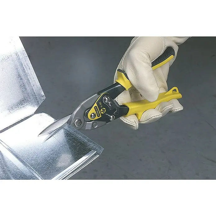 Stanley FatMax Tijeras para chapa - Largo: 250 mm, Longitud de corte: 1,2 mm, Acero - Una mano enguantada usa tijeras para hojalata amarillas para cortar una pieza de chapa metálica. La herramienta son unas tijeras Stanley.