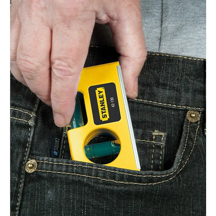 Stanley Taschenwasserwaage - Länge: 84 mm, Anzahl Libellen: 2 Stk. - Eine gelbe Stanley 42-130 Wasserwaage wird in eine Jeanshosentasche gesteckt. Perfekt für präzise Messungen unterwegs.