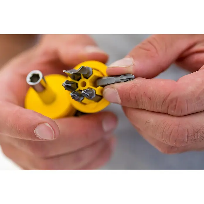 Stanley Vergaser Schraubendreher Stubby 0-66-357 - 8 -tlg. - Nahaufnahme von Händen, die einen gelben Schraubendreher mit verschiedenen Bits halten, ein vielseitiges Werkzeug für Reparaturen und Heimwerkerarbeiten.