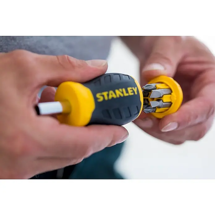Stanley Vergaser Schraubendreher Stubby 0-66-357 - 8 -tlg. - Nahaufnahme eines Stanley Multi-Bit Schraubendrehers, der von Händen gehalten wird, mit gelbem und schwarzem Griff.