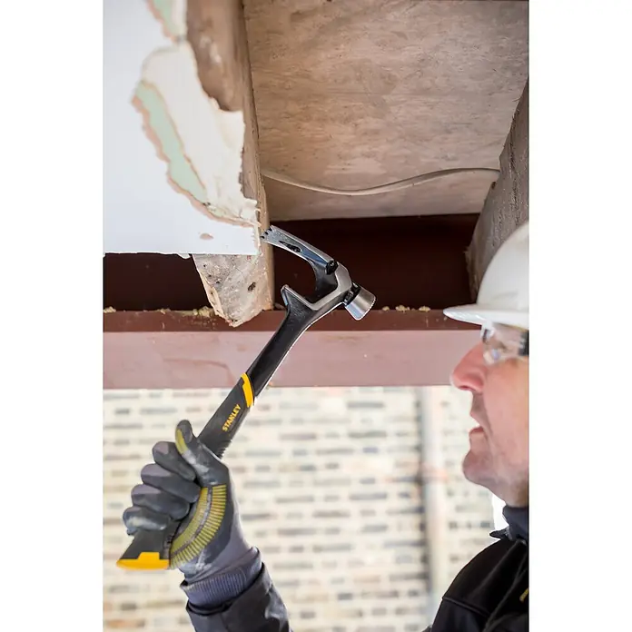 Stanley FatMax Demontagehammer ANTIVIBE - Länge: 410 mm - Ein Bauarbeiter benutzt einen Stanley-Hammer, um ein Stück Putz von einer Decke zu entfernen. Der Hammer ist schwarz mit einem gelben Griff.