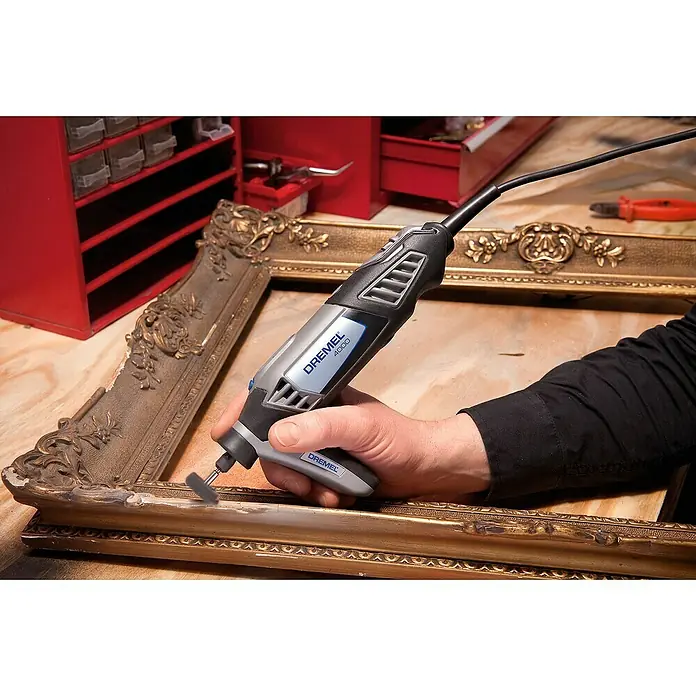 Dremel Präzisionshandgriff Mod. 577 - Passend für: Dremel Multifunktionsgeräte - Ein Dremel 4000 Multifunktionswerkzeug wird verwendet, um einen goldenen Bilderrahmen zu bearbeiten, der auf einer Werkbank liegt.