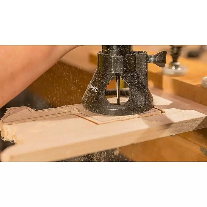 Dremel Mehrzweck-Fräsvorsatz Mod. 565 - 4 -tlg., Arbeitstiefe: 19 mm - Ein Dremel Oberfräsenaufsatz schneidet eine detaillierte Form in helles Holz, dabei entsteht feiner Sägemehl.