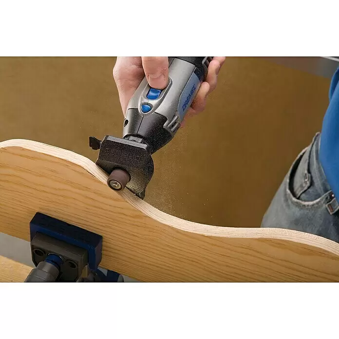 Dremel Modellierungstisch 576 - Passend für: Dremel Multifunktionsgeräte - Eine Person schleift mit einem Dremel-Rotationswerkzeug und Schleifband helles Holz, dabei entsteht feiner Sägemehl.