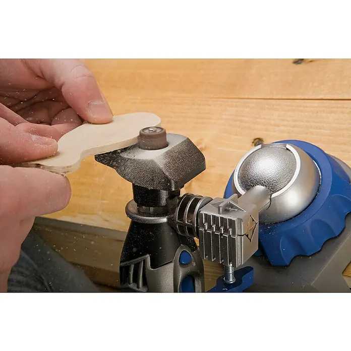 Dremel Modellierungstisch 576 - Passend für: Dremel Multifunktionsgeräte - Nahaufnahme eines Dremel-Werkzeugs beim Schleifen eines Holzstücks, ideal für präzise Detailarbeiten und Modellbauprojekte in der Werkstatt.