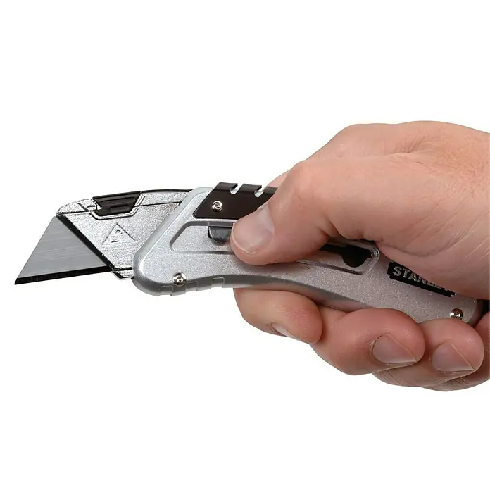 Stanley Taschenmesser Quickslide - 8,7 cm, Silber/Schwarz - Nahaufnahme eines silbernen Stanley-Messer, das in einer Hand gehalten wird und die scharfe Klinge hervorhebt.
