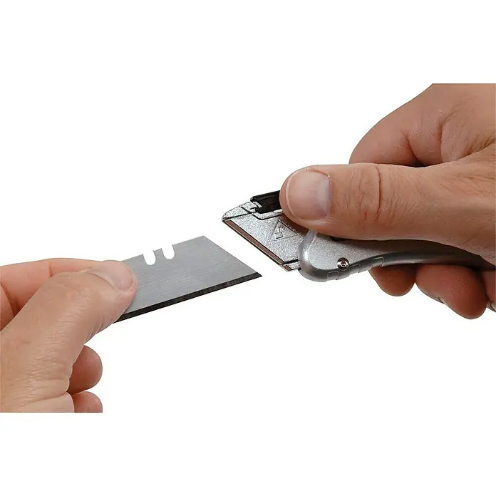 Stanley Taschenmesser Quickslide - 8,7 cm, Silber/Schwarz - Ein silbernes Teppichmesser mit einer Klinge, die von einer Hand gehalten wird, um sie einzusetzen.