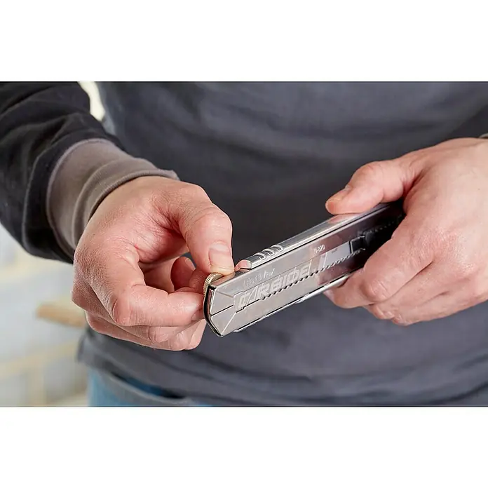 Stanley FatMax Cuttermesser Pro - 25 mm, Abbrechklinge - Nahaufnahme eines Mannes, der ein FastVer Carbide Allzweckmesser justiert, ein Werkzeug für präzise Schneidarbeiten.
