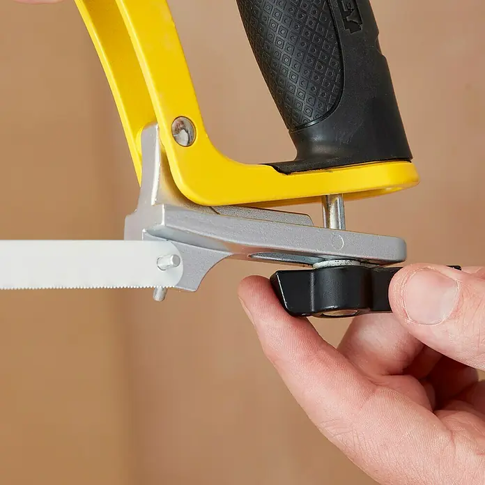 Stanley Metallsäge Turbocut - Blattlänge: 300 mm, Metall - Nahaufnahme einer Bügelsäge mit gelbem Rahmen und schwarzem Griff, die von einer Hand gehalten wird.