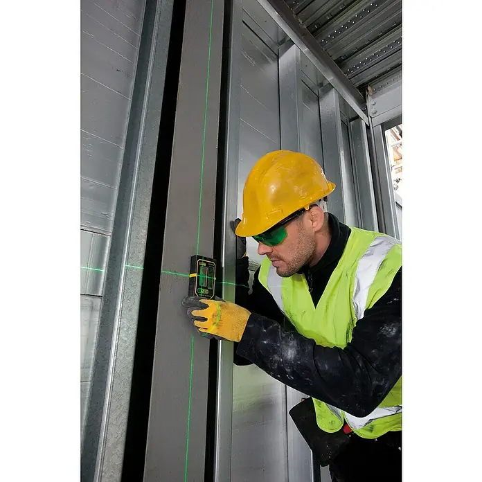 Stanley FatMax Laserempfänger LD200-G - Max. Arbeitsbereich: 50 m - Bauarbeiter justiert Metallrahmen mit einem Laser-Nivelliergerät, das grüne Linien projiziert, um Präzision bei der Arbeit zu gewährleisten.