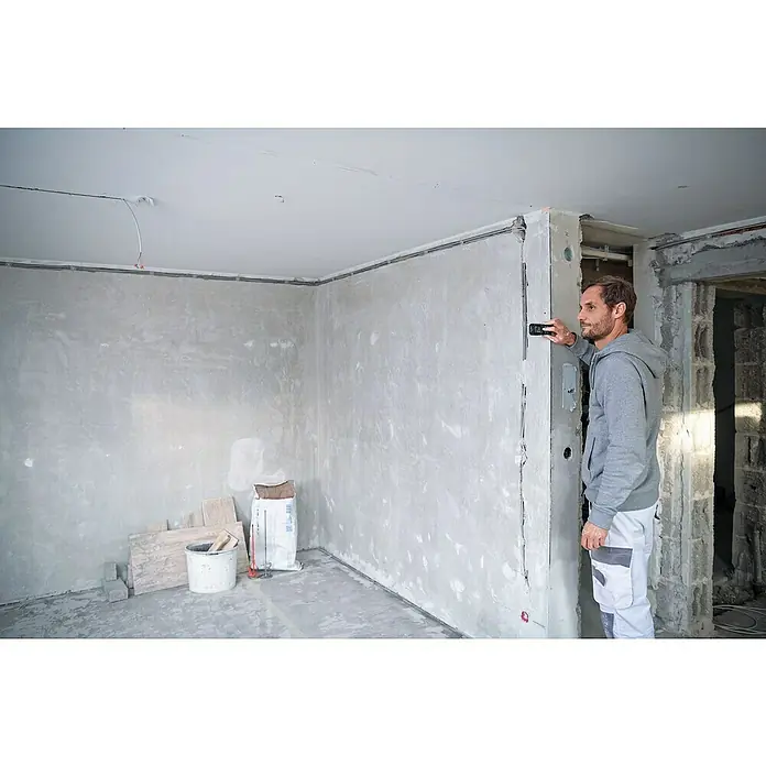 Bosch Professional Laserentfernungsmesser GLM 50-27 CG - Anzahl Akkus: Ohne Akku, Messbereich: 0,05 - 50 m - Ein Bauarbeiter überprüft mit einem digitalen Messgerät die Ausrichtung einer Wand während einer Hausrenovierung. Die Messung ist wichtig für korrekte Ausrichtung.