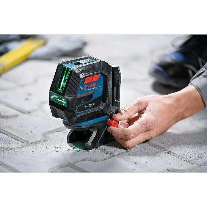 Bosch Professional Kombilaser GCL 2-50 G mit Bosch Professional Stativ BT 150 - Arbeitsbereich: 50 m (mit Empfänger) - Ein schwarzer und blauer Bosch Laserlevel mit grünen Linien wird von einer Hand auf Pflastersteinen justiert.