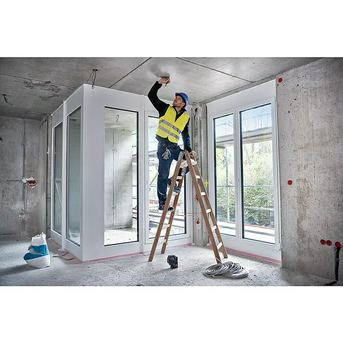 Bosch Professional Láser combinado GCL 2-50 - Zona de trabajo: 50 m (con receptor) - Un trabajador de la construcción en una escalera en una habitación inacabada con ventanas y paredes en bruto, trabajando en el techo.