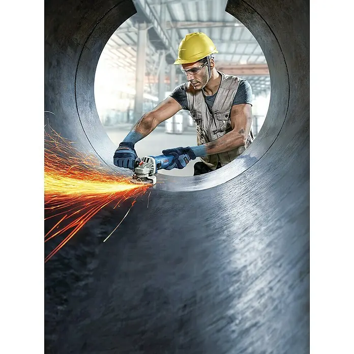 Bosch Professional Elektro-Winkelschleifer GWS 900 - 900 W, Durchmesser Scheibe: 125 mm, Leerlaufdrehzahl: 11.000 U/min - Ein Mann mit Schutzhelm und Schutzbrille benutzt eine Bosch Schleifmaschine, um ein Metallrohr zu bearbeiten, wobei Funken fliegen.