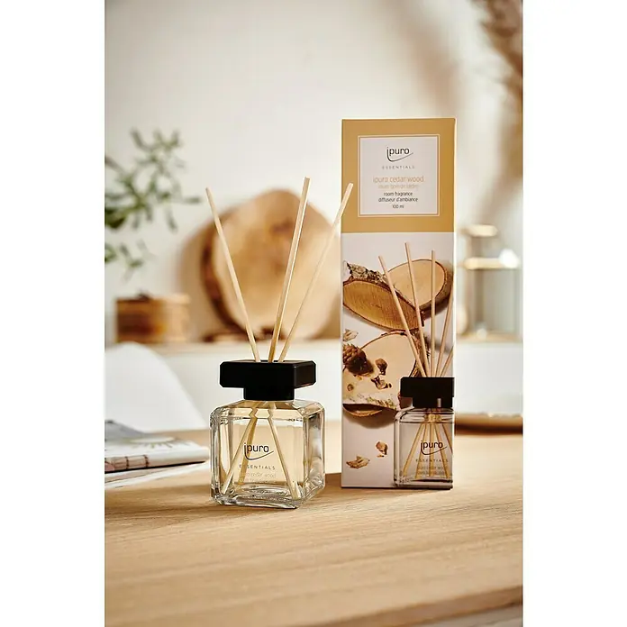 Ipuro Essentials RaumduftCedar Wood, 100 ml - Nahaufnahme von "ipuro cedar wood" Raumduft-Diffuser mit Holzstäbchen und der zugehörigen Verpackung.