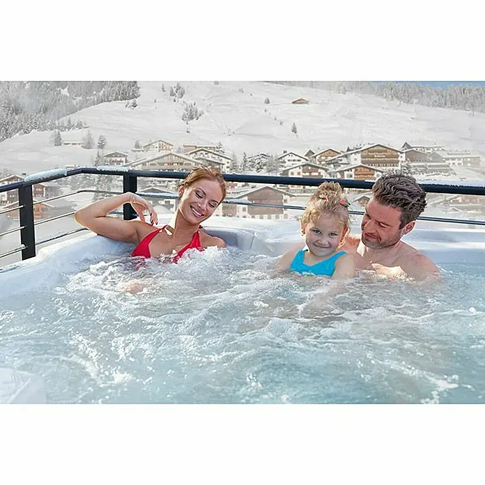 Camargue Außen-Whirlpool Harmony - 200 x 200 x 87 cm, Grau/Weiß, Max. Personenzahl: 6 - Familie entspannt im Whirlpool mit Blick auf die verschneiten Berge. Genießen Sie das warme Wasser und die atemberaubende Aussicht.
