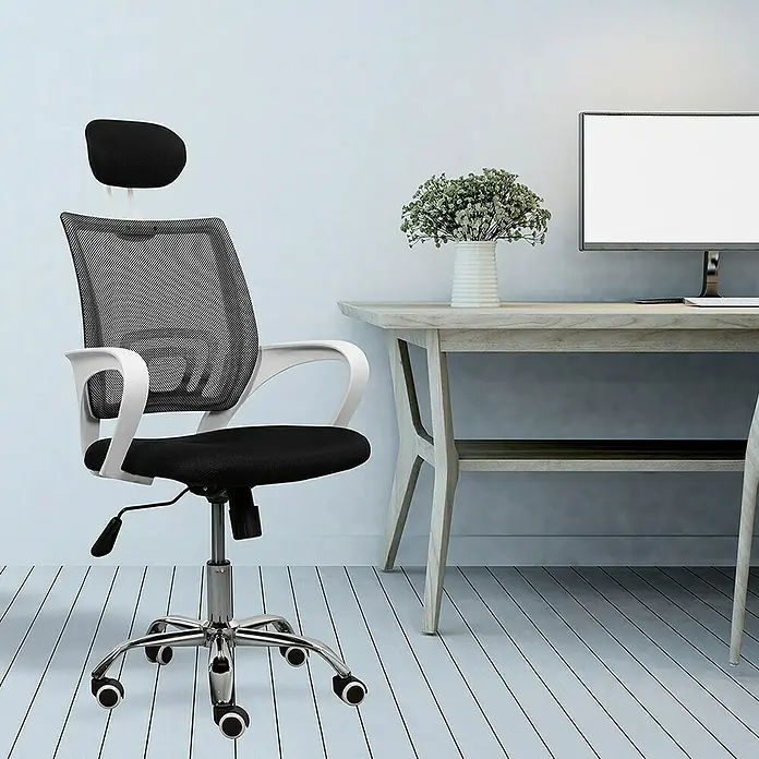 Silla de oficina Marta - Blanco/Negro, Reposacabezas - Una silla ergonómica de oficina con respaldo de malla, reposacabezas ajustable y base cromada frente a un escritorio.