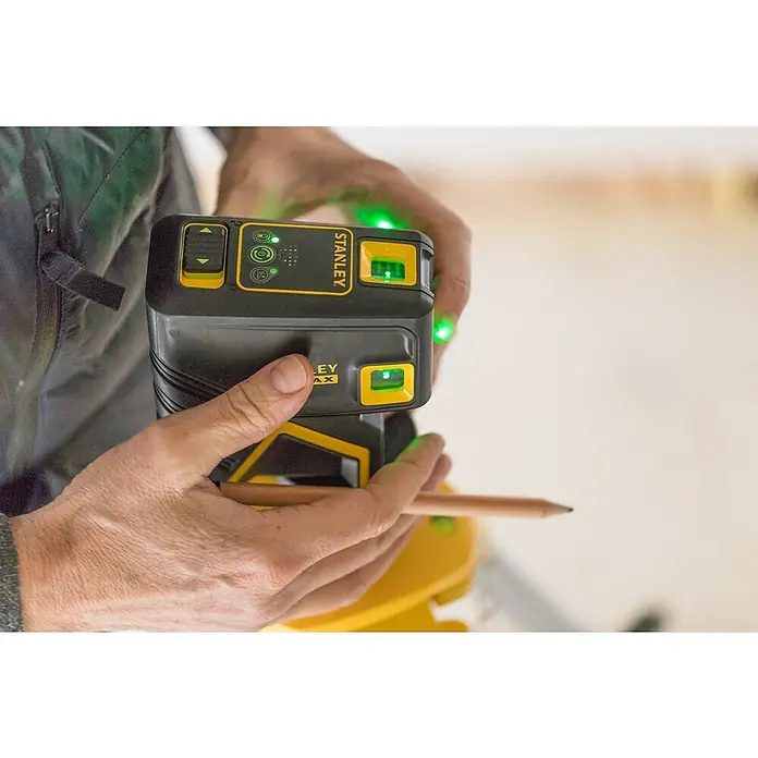 Stanley FatMax Punktlaser FMHT1-77437 - Max. Arbeitsbereich: 45 m, Stativ-Gewinde: ¼″ - Nahaufnahme eines Stanley MAX Lasernivelliergeräts in den Händen einer Person, das grüne Laserstrahlen projiziert.