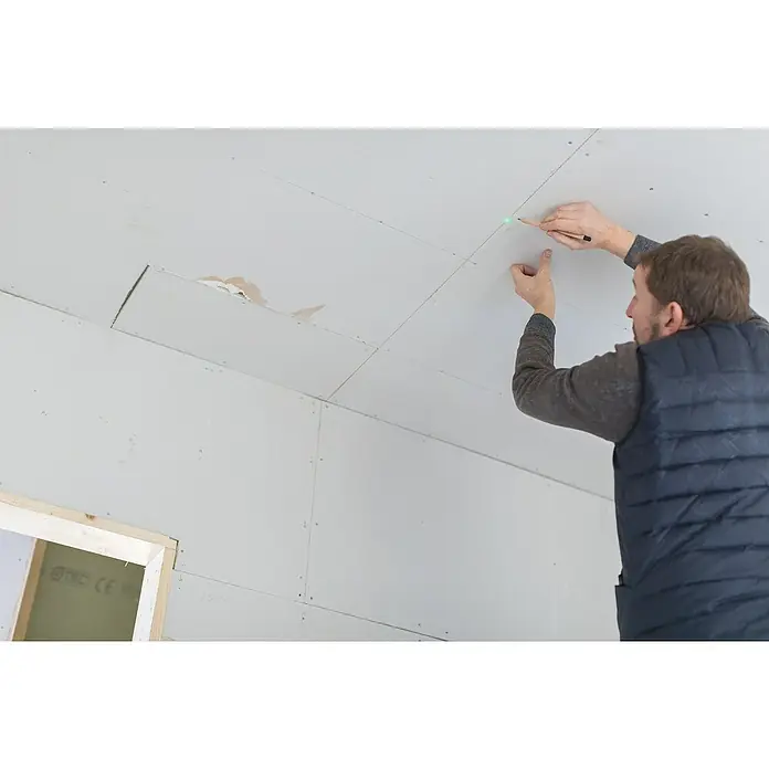 Stanley FatMax Punktlaser FMHT1-77437 - Max. Arbeitsbereich: 45 m, Stativ-Gewinde: ¼″ - Mann, der mit Bleistift eine Linie an einer Gipskartonplatte an der Decke zieht, mit einem Laserpointer als Richtlinie für die Reparatur.