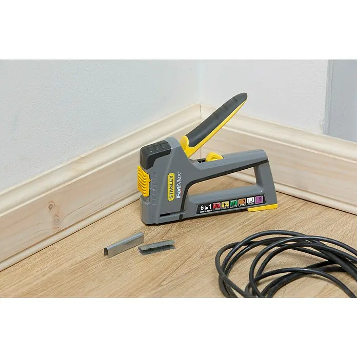 Stanley FatMax Kombi-Handtacker TR75 - Klammertiefe: 14 mm, Geeignet für: Möbelaufarbeitungen - Nahaufnahme eines Stanley FatMax 6-in-1-Tackers mit Heftklammern und einem schwarzen Kabel auf einem Holzboden.