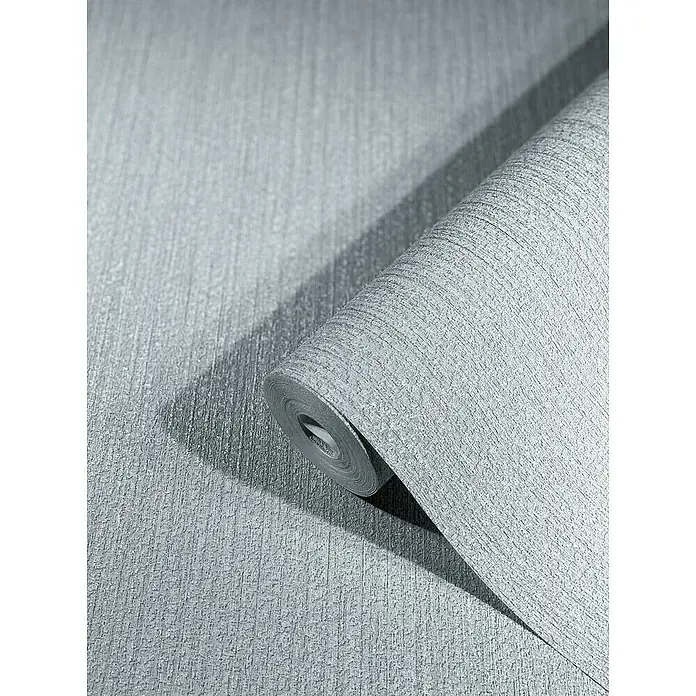 SCHÖNER WOHNEN-Kollektion New Spirit Vliestapete Struktur - Grau, Uni, 10,05 x 0,53 m - Nahaufnahme einer Rolle grauer strukturierter Tapete mit einem subtilen Schatten, die Textur und Farbe des Produkts hervorhebt.