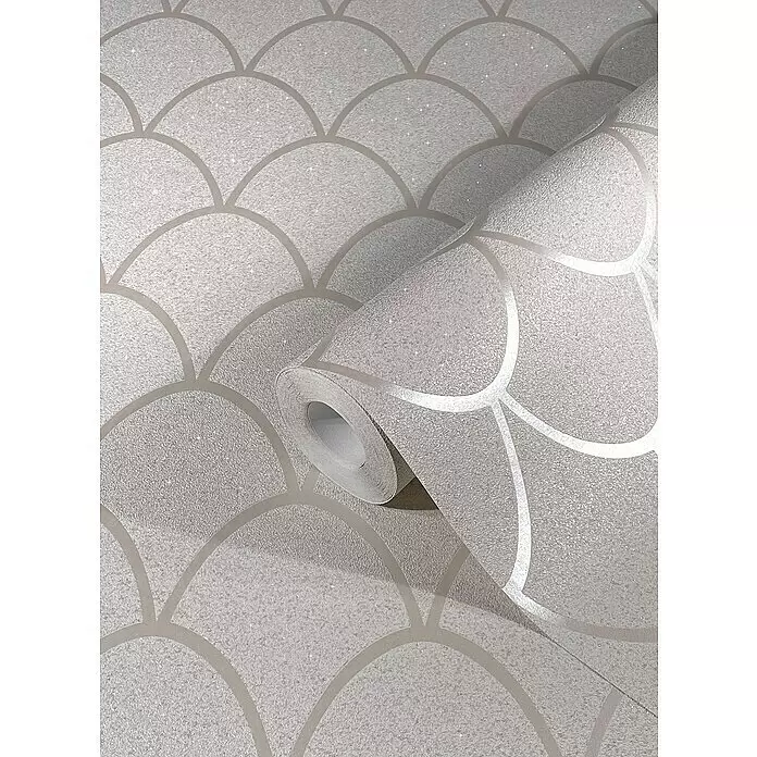 SCHÖNER WOHNEN-Kollektion New Spirit Vliestapete - Beige, Grafisch, 10,05 x 0,53 m - Glitzernde hellgraue Tapete mit metallischem Schuppenmuster, teilweise abgerollt auf einer flachen Oberfläche.