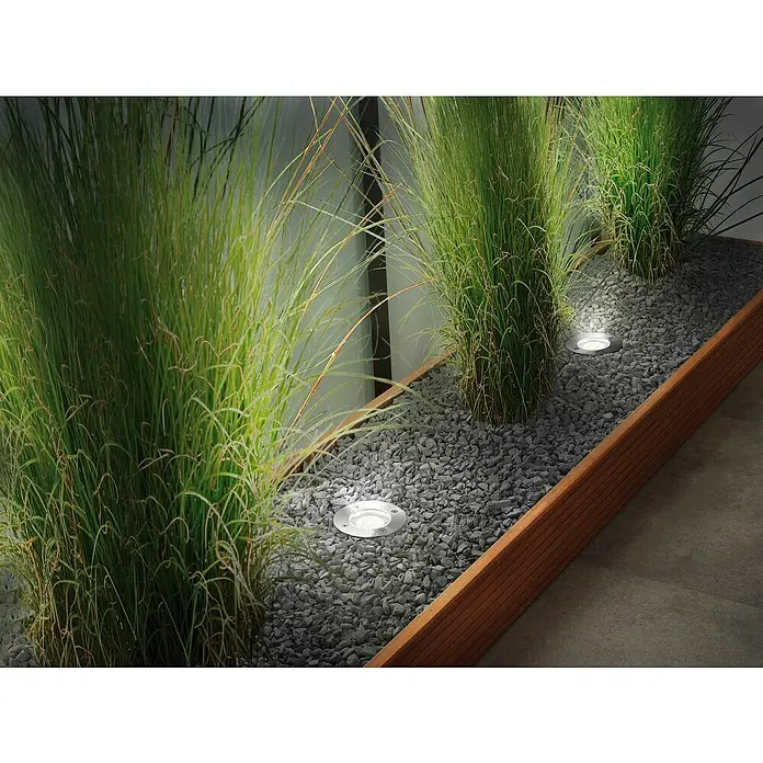 Paulmann Plug & Shine Basis-Set LED-Bodeneinbauleuchte Smart Home Zigbee - 3,6 W, Silber, Ø x H: 9,8 x 9,2 cm, Per App steuerbar, IP65 - Außenleuchten in einem Kiesbeet mit Ziergräsern. Die runden Einbaustrahler sorgen für stimmungsvolle Beleuchtung im Garten.