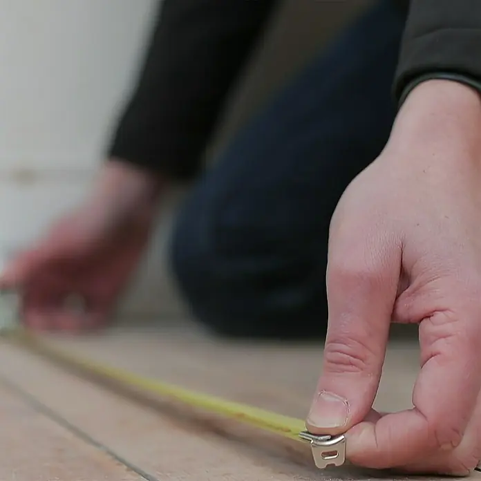 Stanley Kapselmaßband Powerlock - 5 m - Eine gelbe Messlatte, die von einer Person benutzt wird, um ein Projekt zu messen.