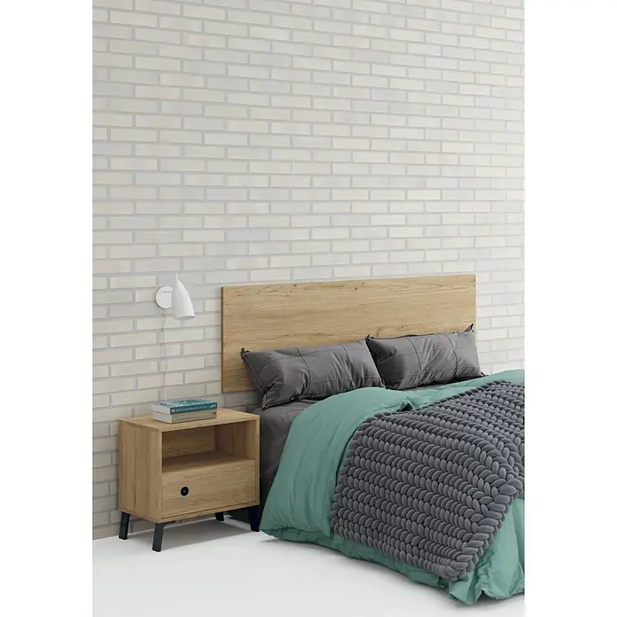 Muebles Pitarch Camila Cabecero de cama con mesitas - Roble gold, 3 pzs. - Un dormitorio con cabecero de madera clara, almohadas grises y una manta gris sobre una ropa de cama verde.