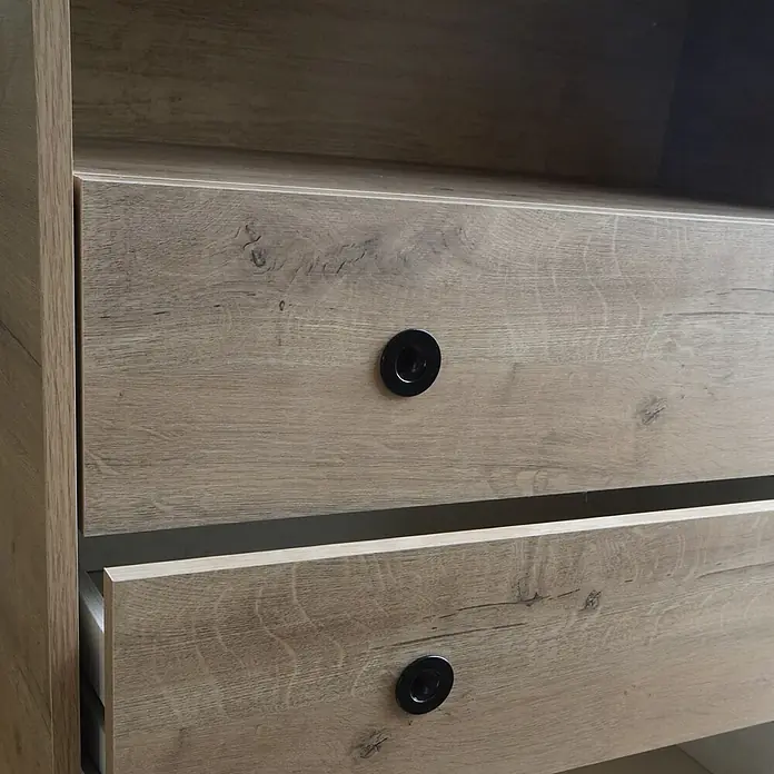Muebles Pitarch Camila Cabecero de cama y cómoda - 2 pzs., Roble gold - Primer plano de una cómoda con dos cajones y pomos negros. Los cajones son de madera clara.
