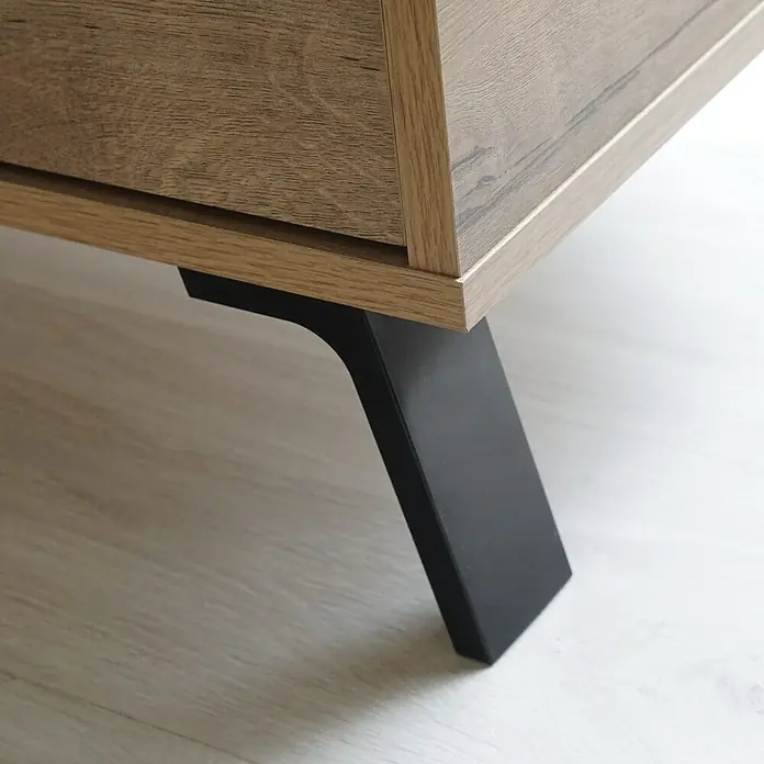 Muebles Pitarch Camila Cabecero de cama con mesita - 2 pzs., Roble gold - Primer plano de un moderno mueble de madera que muestra una elegante pata metálica negra, destacando la estética minimalista del mueble.
