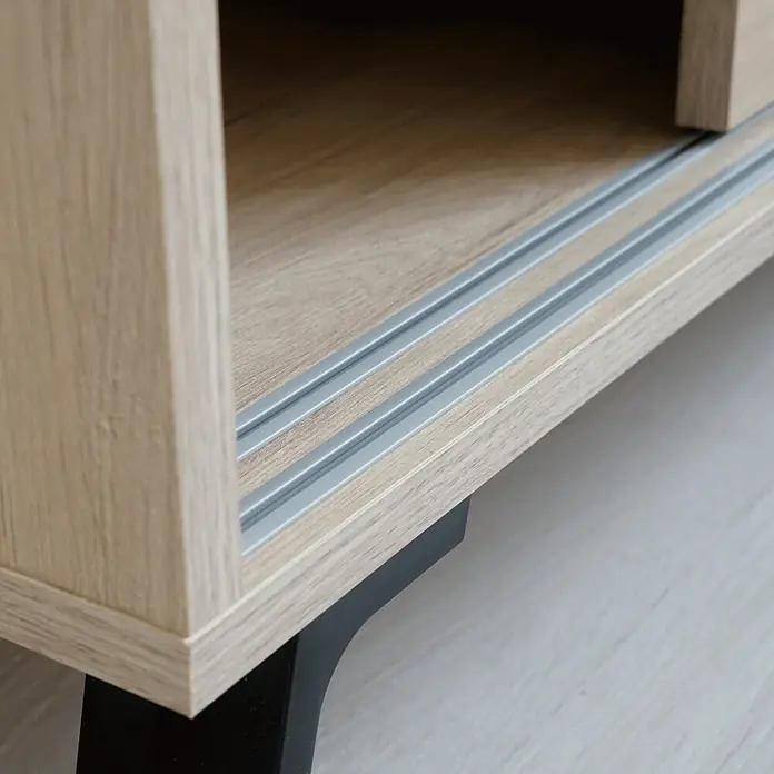 Muebles Pitarch Kamet Aparador - L x An x Al: 40 x 120 x 87 cm, Roble aurora - Primer plano de un estante de madera clara con rieles grises y una elegante pata negra. Ideal para espacios modernos.