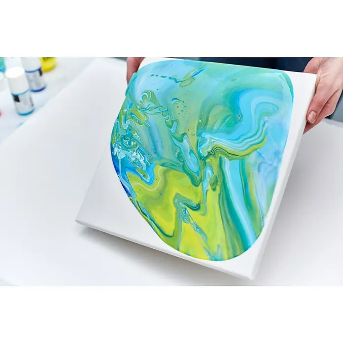 Liquitex Professional Gießmedium Gloss - 473 ml, Transparent - Nahaufnahme eines mit fließenden Blau-, Grün- und Gelbtönen bemalten quadratischen Kunstleinen.