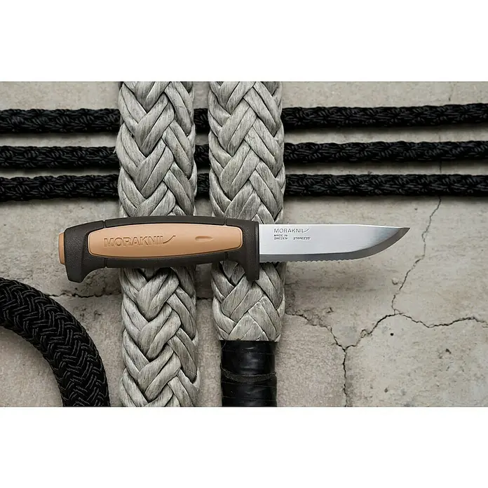 Morakniv Messer Pro Rope Sealed - Klingenlänge: 91 mm, Art Klinge: Gezahnte Schneide - Nahaufnahme eines Moraknil Messers mit braun-schwarzem Griff, liegend auf grauem Seil, dessen rostfreies Stahlblatt scharf und einsatzbereit ist.