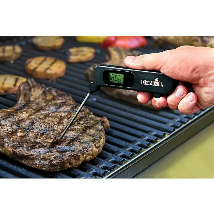 Char-Broil Grill-Thermometer - Länge: 25 cm, Klappbar - Nahaufnahme eines Char-Broil-Thermometers, das die Temperatur eines saftigen Steaks auf einem Grill misst, um perfekte Ergebnisse zu gewährleisten.
