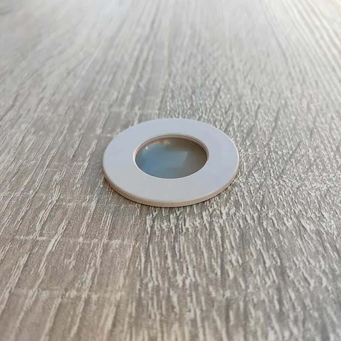 Muebles Pitarch Tibet Armario de puertas correderas y zapatero - Roble - Primer plano de un marco redondo blanco para luz empotrable LED en una superficie de madera, mostrando un diseño moderno y funcionalidad.