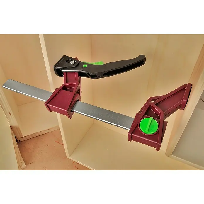 Piher Tornillo de apriete monomanual Light Pal - Anchura de sujeción: 160 mm, Fuerza de tensión: 1.177 N - Una abrazadera de una mano roja y gris se utiliza para pegar un armario. La herramienta es una ayuda esencial para la carpintería.