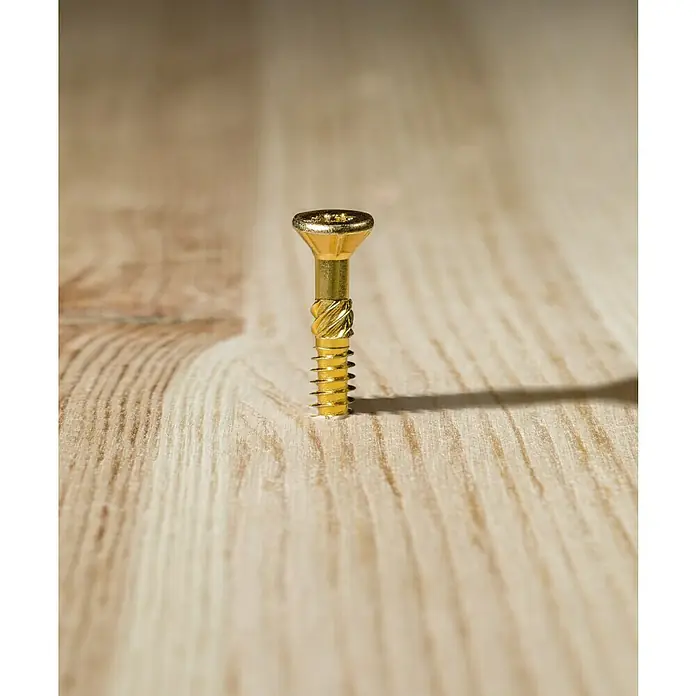 Profi Depot Mehrzweck-Schraube Turbo Drill - Ø x L: 4 x 50 mm, TX für TORX-Antriebe, Senkkopf, 200 Stk. - Nahaufnahme einer einzelnen goldenen Schraube, die auf einer hellen Holzoberfläche steht. Die Schraube wirft einen deutlichen Schatten.