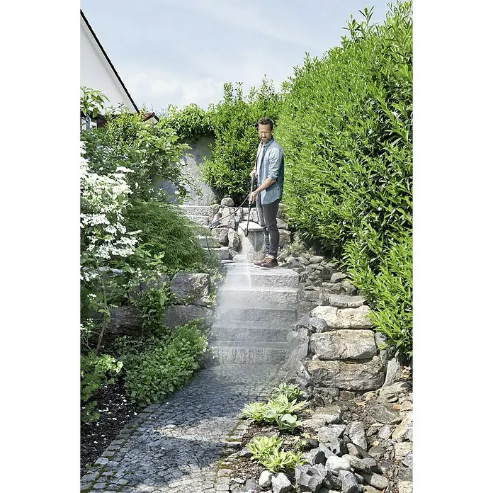 Kärcher Hochdruckreiniger K 5 Pure Home - 2.100 W, Betriebsdruck: 20 bar - 145 bar - Ein Mann reinigt eine Steintreppe im Freien mit einem Kärcher Hochdruckreiniger, umgeben von üppigem Grün.
