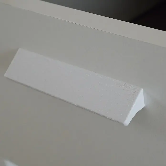 Muebles Pitarch Tibet Cómoda - L x An x Al: 40 x 74 x 78 cm, Blanco, Número de cajones: 4 ud. - Primer plano de un tirador de mueble rectangular blanco con bordes redondeados, sujeto a una superficie blanca lisa.