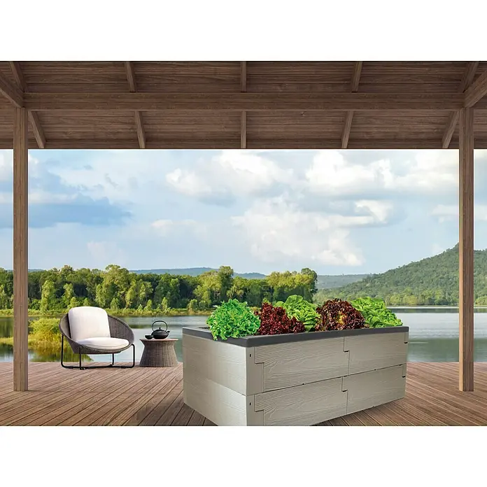 Juwel Hochbeet Timber - 130 x 60 x 20 cm - Ein erhöhter Pflanzkasten mit Salatpflanzen steht auf einer Holzterrasse mit Seeblick im Hintergrund.