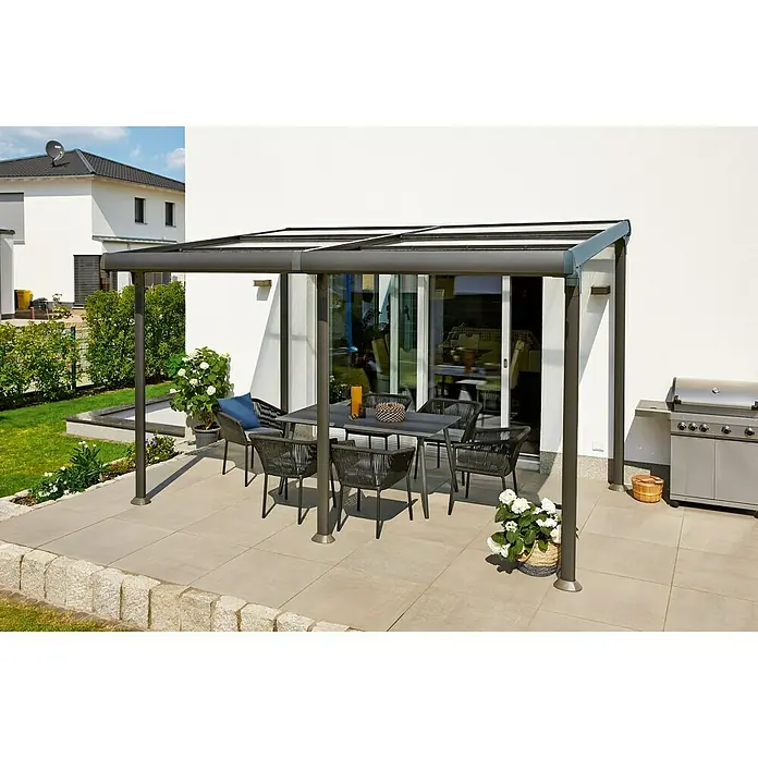 Sunfun Pérgola adosada Sera - An x Pr: 400 x 300 cm, Antracita, Aluminio - Una cubierta de patio moderna con una mesa de comedor y sillas debajo, al lado de una parrilla. La cubierta proporciona protección y estilo para el exterior.