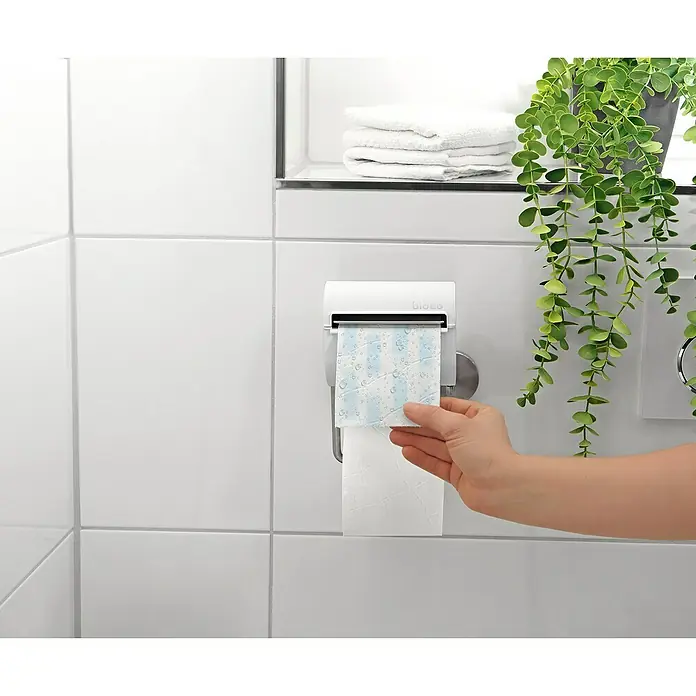 Toilettenpapierbefeuchter bideo - Weiß/Chrom, Glänzend - Eine Nahaufnahme eines Bideo Toilettenpapierspenders, aus dem eine Person ein Blatt Toilettenpapier entnimmt.