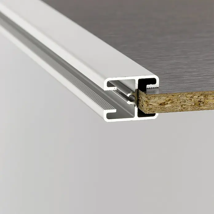 Room Plaza Easy Kranzprofil - Passend für: Room Plaza Easy Schiebetür-Bau-Sets, 1.200 mm, Silber - Detailaufnahme einer silbernen Aluminiumkante, die an einer Holzarbeitsplatte befestigt ist, befestigt mit Schrauben für zusätzliche Stabilität.
