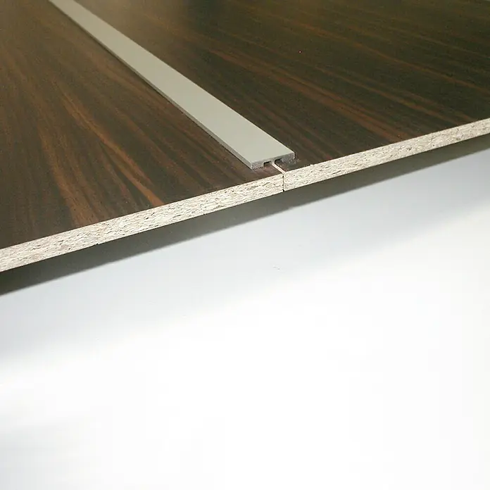 Room Plaza Easy H-Profil - Passend für: Room Plaza Easy Schiebetür-Bau-Sets, Silber - Detailaufnahme einer Holzplatte mit Dekor und einer grauen T-Profilleiste, die zwei Platten verbindet. Ideal für Möbelbau und Innenausbau.