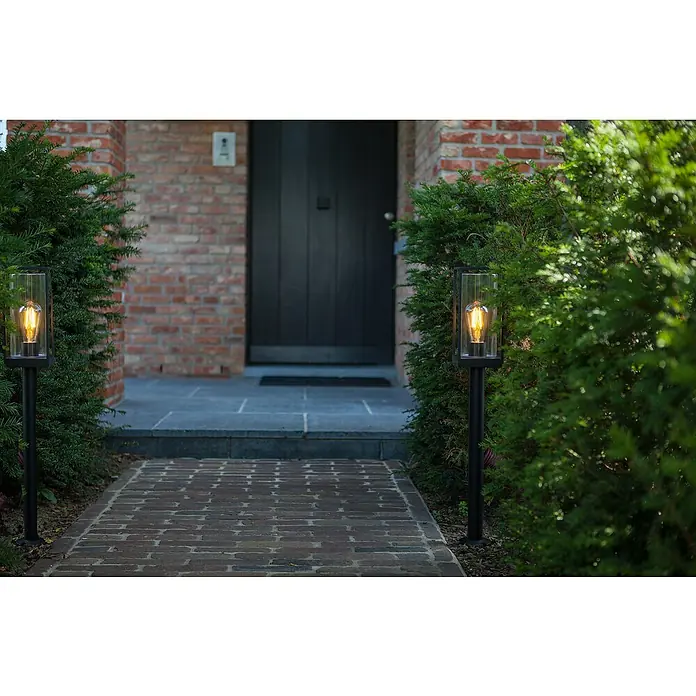 Lutec Lámpara de pie para exterior Flair - 40 W, Color del marco: Negro, 120 x 120 x 750 mm, Sin bombillas - Una escena con dos luces de exterior que iluminan un camino hacia una puerta principal. Las luces tienen un diseño moderno.