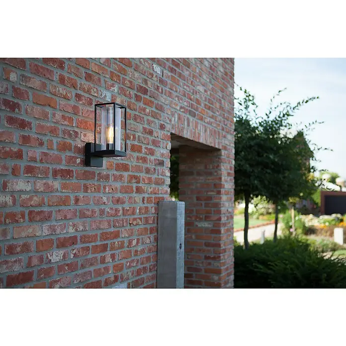 Lutec Aplique exterior Flair - 40 W, 12 x 17,2 x 31,3 cm, Negro, IP44 - Lámpara de pared exterior moderna con cristal transparente y marco negro montada sobre una pared de ladrillo. La luminaria proporciona iluminación exterior.
